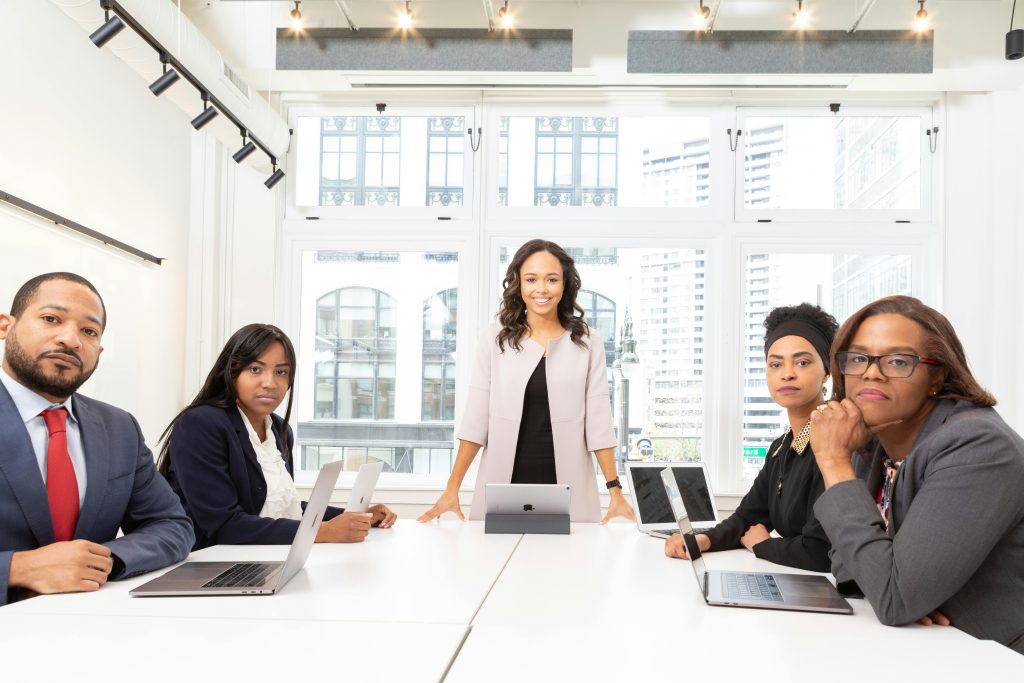 A diverse group of professionals having a meeting in a modern office setting with large windows.